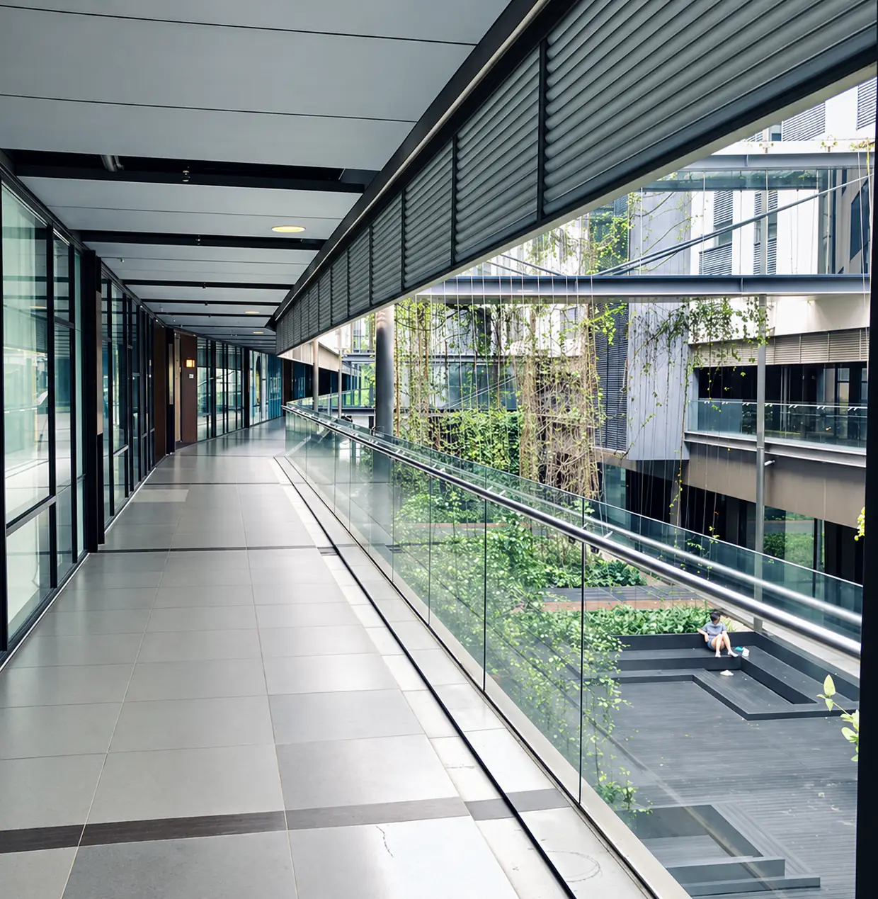 A glass-railed corridor overlooking the planted courtyard